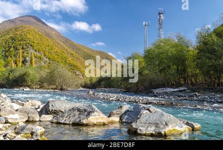 paesaggio con due torri cellulari vicino a un fiume di montagna Foto Stock