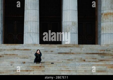 Melbourne, Australia, 12 aprile 2020. Una donna siede da sola sui gradini del Santuario della memoria durante la crisi COVID-19 a Melbourne, Australia. Credit: Dave Hewison/Alamy Live News Foto Stock