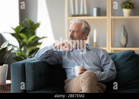 Uomo più anziano pensieroso seduto sul divano da solo, sentendosi solo Foto Stock