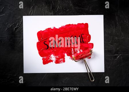 Rimani a casa, dipinto a mano su vernice rossa, messaggio di quarantena Covid-19 Foto Stock