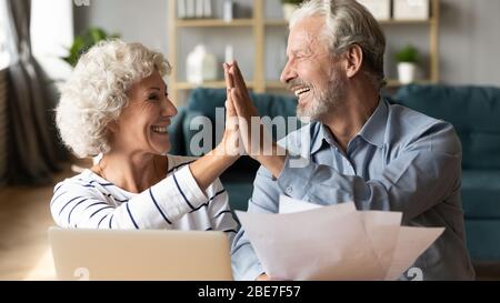 Eccitata coppia più anziana che dà cinque alti, celebrando le buone notizie Foto Stock