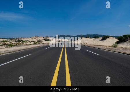 Strada costiera vuota circondata da sabbia Foto Stock