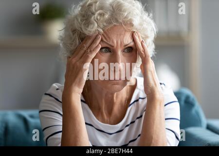 Donna matura triste che tocca i templi da vicino, sensazione di malessere Foto Stock