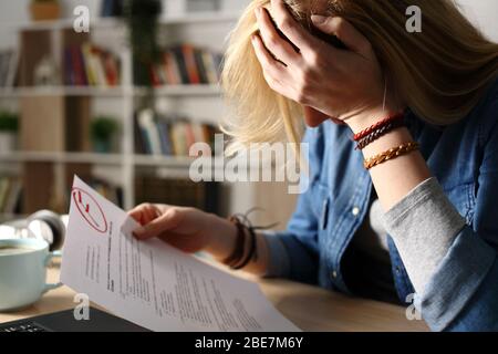 Primo piano di uno studente triste lamentarsi di un esame fallito seduto su una scrivania a casa di notte Foto Stock