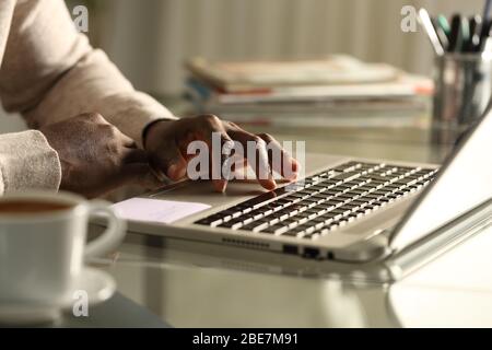 Primo piano della mano nera dell'uomo utilizzando il touchpad del notebook sulla scrivania di notte Foto Stock