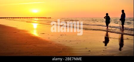 Banner, pagina Web o modello di copertina. Dimensioni standard. I pensionati camminano sulla bellissima spiaggia del mattino durante l'alba. Spazio copia e rati panoramici Foto Stock