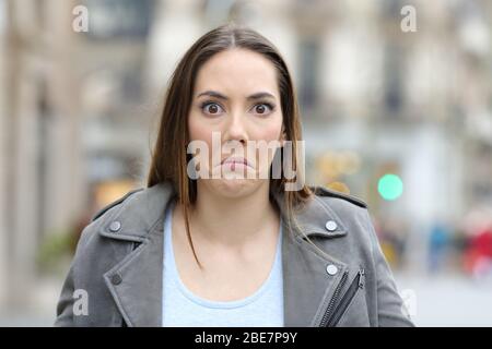 Vista frontale ritratto di una giovane donna confusa guardando la macchina fotografica in strada Foto Stock