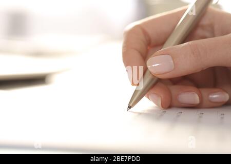 Primo piano della mano della donna che compila il modulo con la penna su una scrivania Foto Stock