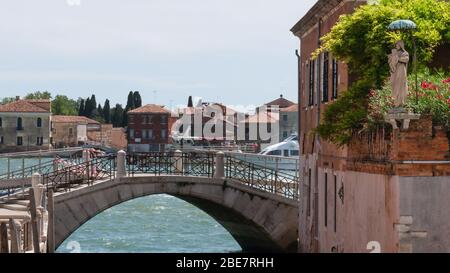 Statua di Santa Maria trovata in un piccolo angolo di strada di Venezia, Italia. Vegetazione verde. Foto Stock