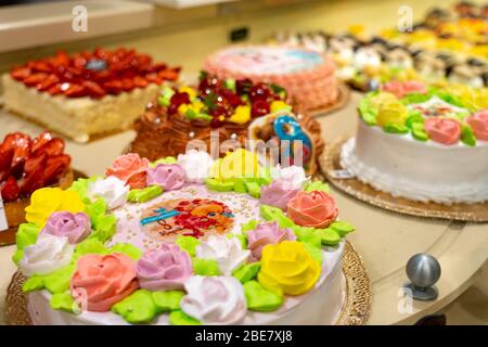 Torte e pasticcini in una vetrina. Pasticceria con varietà di ciambelle, crème brulee, torte con frutta e frutti di bosco. Foto Stock