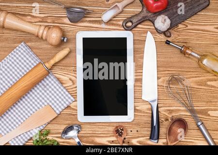 Tablet con schermo vuoto e cucina e utensili da cucina diversi. Foto Stock