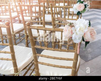 Le sedie di nozze decorano con i fiori bei per la cerimonia nuziale. Allestito per matrimoni con sedie dorate. Foto Stock