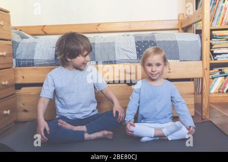 Bambini che fanno yoga online in camera da letto Foto Stock