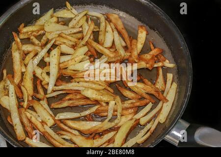 Friggere patatine fritte in olio d'oliva caldo in cucina casalinga. Vista dall'alto della preparazione di patate fritte preparate in casa su una pentola con olio bollente. Foto Stock