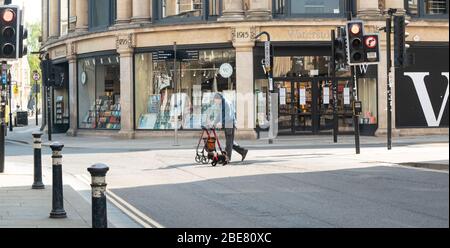 Un uomo disabile che utilizza una struttura a piedi su ruote, cammina i suoi cani la Domenica di Pasqua mattina in strade deserte, Oxford, Oxfordshire, Regno Unito Foto Stock