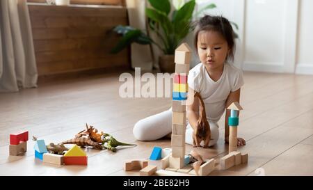 Piccola ragazza asiatica seduta su pavimento caldo gioca blocchi di legno Foto Stock