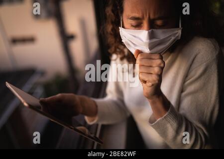 Donna che indossa una maschera facciale a casa. Distanza sociale in quarantena durante l'epidemia di coronavirus Foto Stock