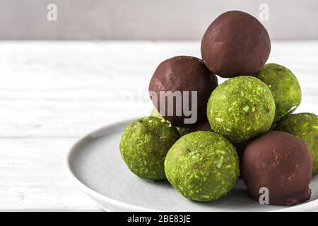 Palle verdi di energia di matcha con palle di matcha in glassa di cioccolato. Dessert sano di cibo vegano. Primo piano Foto Stock