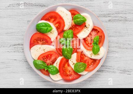 Deliziosa insalata di caprese con pomodori maturi e mozzarella con foglie di basilico fresco. Cucina italiana, vista dall'alto Foto Stock