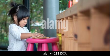 I bambini imparano a giocare con il colorato giocattolo in legno sul tavolo a casa. Preschool giovane ragazza concentrarsi con l'attrezzatura educativa in recesso termine di nuovo a. Foto Stock