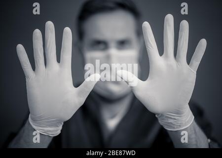 Focolaio COVID-19. Aiuto per fermare la diffusione del virus. Medico o infermiere che indossa maschera chirurgica facciale e guanti DPI che mostrano le mani in STOP gesture. Soggiorno s Foto Stock