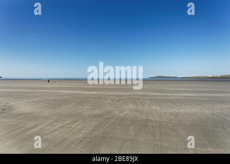 Nella foto: Un uomo solitario gioca con un frisbee a Poppit Sands, Galles, Regno Unito. Mercoledì 08 Aprile 2020 Foto Stock