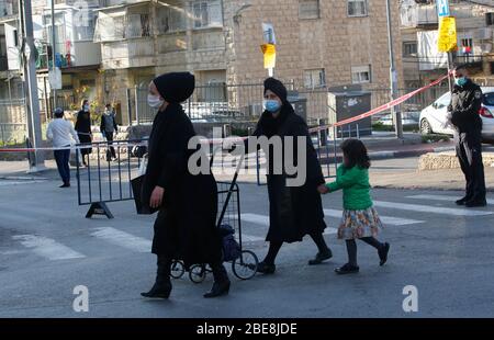 Gerusalemme. 12 aprile 2020. Gli ebrei ultra-ortodossi che indossano maschere facciali sono visti nel quartiere bloccato di Mea Shearim a Gerusalemme, in mezzo alla pandemia di coronavirus il 12 aprile 2020. Israele ha annunciato diversi quartieri di Gerusalemme come "zone ristrette" come parte della lotta contro il romanzo coronavirus, l'Ufficio del primo Ministro israeliano e il Ministero della Salute ha annunciato Domenica. La decisione ha avuto effetto domenica alle 12.00 e sarà valida fino ad aprile 15. Credit: Gil Cohen Magen/Xinhua/Alamy Live News Foto Stock