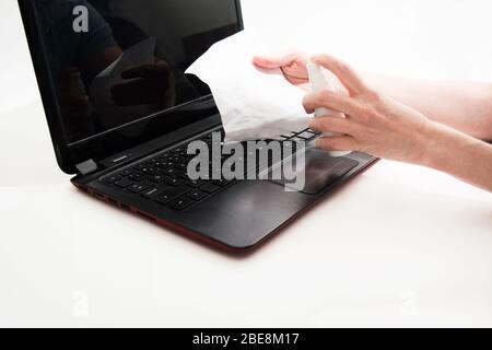 Spruzzatura manuale femmina su tessuto liquido speciale per pulizia e disinfezione laptop su sfondo bianco. Spazio di copia Foto Stock