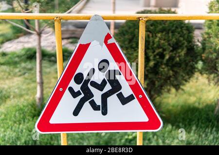 Primo piano dei bambini di età e graffiati che attraversano il cartello stradale Foto Stock