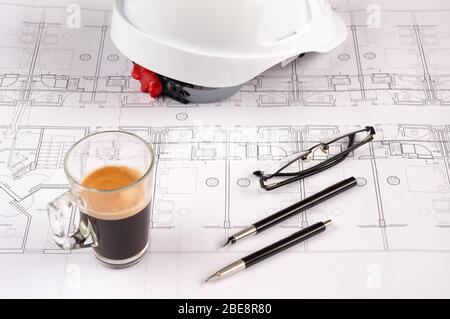 Architetti luogo di lavoro - progetti architettonici con casco di sicurezza, occhiali, penna di propulsione e caffè sul tavolo. Vista dall'alto. Foto Stock