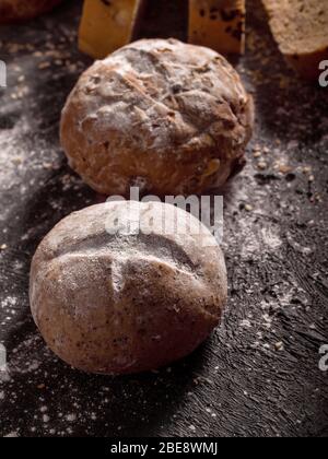 Primo piano le focacce rustiche di pane poste su sfondo nero di legno. Foto Stock