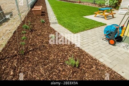 Giardinaggio - Giardino con nuovo prato fresco e superficie di pacciame di corteccia per ridurre la crescita delle erbacce Foto Stock