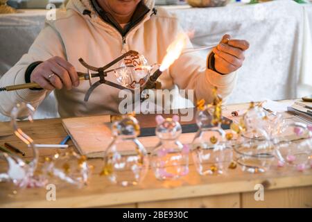 Artigiano decorazione di oggetti in vetro utilizzando una torcia. Foto Stock