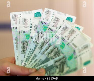 Russian money.A giovane uomo è in possesso di banconote con un valore nominale di 1000 rubles.A molto denaro in mano, primo piano. Foto Stock