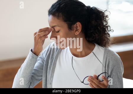 Stanco ragazza togliere gli occhiali, massaggio nasello ponte Foto Stock