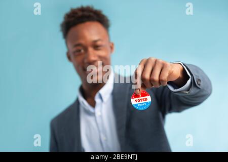 Primo piano della campagna patriottica Button in mano di un uomo d'affari afro-americano Foto Stock