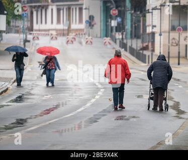 13 aprile 2020, Hessen, Francoforte sul meno: In caso di pioggia leggera, gli escursionisti camminano a coppie lungo una strada bagnata sulle rive del meno, che è chiusa al traffico. Foto: Frank Rumpenhorst/dpa Foto Stock