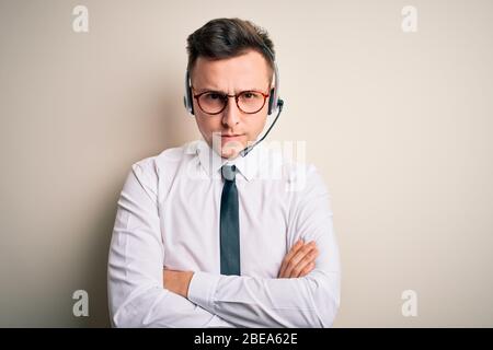 Giovane uomo d'affari caucasico che indossa cuffie per contact centre al servizio clienti, con un'espressione scettica e nervosa, che disapprova la faccia con crosse Foto Stock