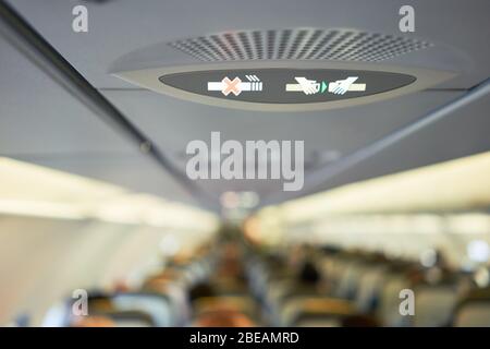 Passeggeri e equipaggio seduti sui sedili dell'aereo, vista dei passeggeri e degli assistenti all'interno della cabina Foto Stock