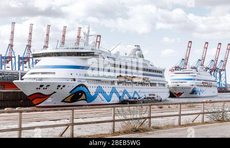 13 aprile 2020, Amburgo: Le navi da crociera AIDAaura (l) e AIDAcara sono ormeggiate al terminal dei traghetti di Steinwerder. Come misura per contenere la pandemia corona, hanno temporaneamente sospeso le loro crociere. Foto: Markus Scholz/dpa Foto Stock