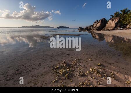 Source d'argent granito massi spiaggia bassa marea acqua Oceano Indiano colorato tramonto vista Foto Stock