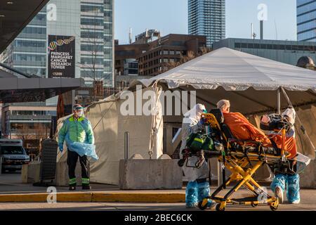 Un uomo viene portato via su una barella al Covid-19 Assessment Center presso il Women's College Hospital Assessment Centre nel centro di Toronto, Canada, 17 marzo 2020. Tra le misure di sicurezza dirette a rallentare la diffusione del virus COVID-19, la Provincia dell'Ontario ha dichiarato uno stato di emergenza il 17 marzo 2020. Le nuove norme limiteranno in gran parte le persone che si trovano nei ristoranti e chiuderanno bar, palestre, chiese, tra le altre cose. Foto Stock