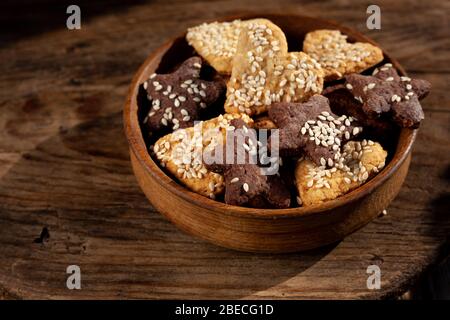 Biscotti fatti in casa con semi di sesamo su un piatto di legno su sfondo di legno. Cibo fatto in casa. Foto Stock