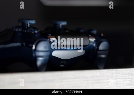 Brecht, Belgio - febbraio 1 2020: Un ritratto scuro e ravvicinato di un controller sony playstation 4 che emerge dal buio su un tavolo. Pronto per essere utilizzato Foto Stock