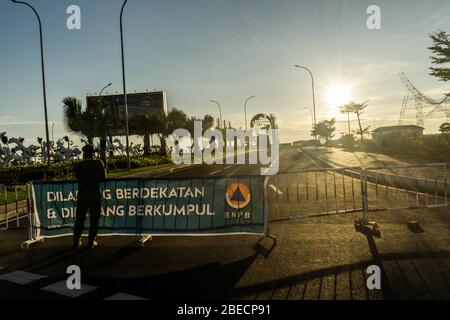 Makassar, Sulawesi del Sud, Indonesia. 13 Aprile 2020. Makassar City Servizio civile unità di polizia guardia sulla strada che è l'accesso alle attrazioni turistiche che sono ora chiusi durante la pandemia Covid-19. Il governo indonesiano ha riferito che fino a lunedì il numero di persone colpite da Covid-19 era di 4,557, con 399 morti. Credit: Herwin Bahar/ZUMA Wire/Alamy Live News Foto Stock