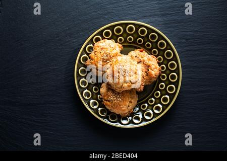 Cucina orientale concetto casalinga cinese Sesame cookie in piastra di ceramica verde su bordo di pietra ardesia nera con spazio copia Foto Stock