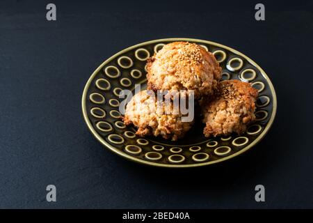 Cucina orientale concetto casalinga cinese Sesame cookie in piastra di ceramica verde su bordo di pietra ardesia nera con spazio copia Foto Stock