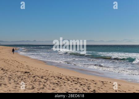 Tarifa, Spagna. 3 febbraio 2020. Uomo che cammina da solo sulla spiaggia di Bolonia vicino a Tarifa con le montagne africane sullo sfondo Foto Stock