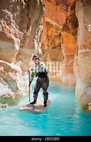 Metà uomo adulto paddleboarding sulle rive di un fiume. Foto Stock