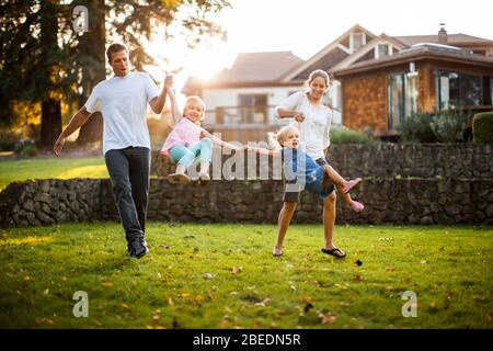 Genitori felici che giocano con le loro due figlie giovani nel cortile Foto Stock